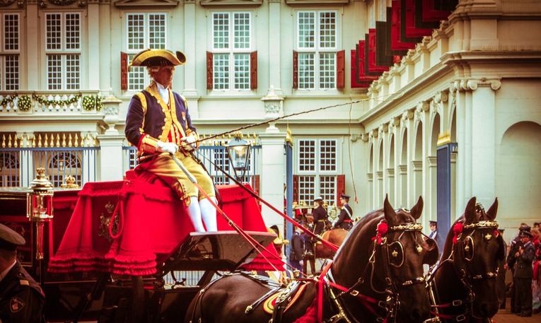 Den Haag The Hague, Netherlands - September 17, 2013 : Royal Horse and carriage, with a guard on top with decorated suit are leaving the royal palace noordeinde